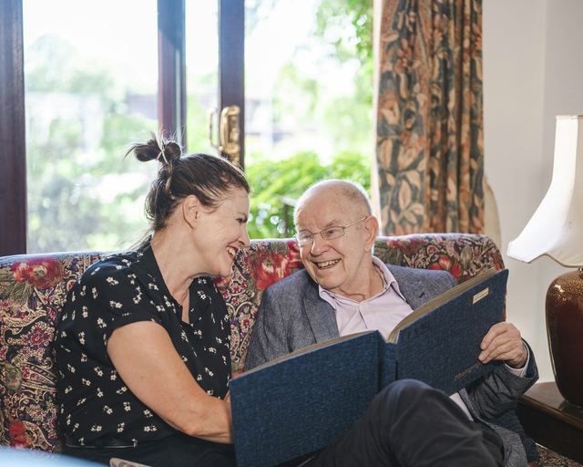 Een vrouw en een oudere man bekijken samen een fotoalbum